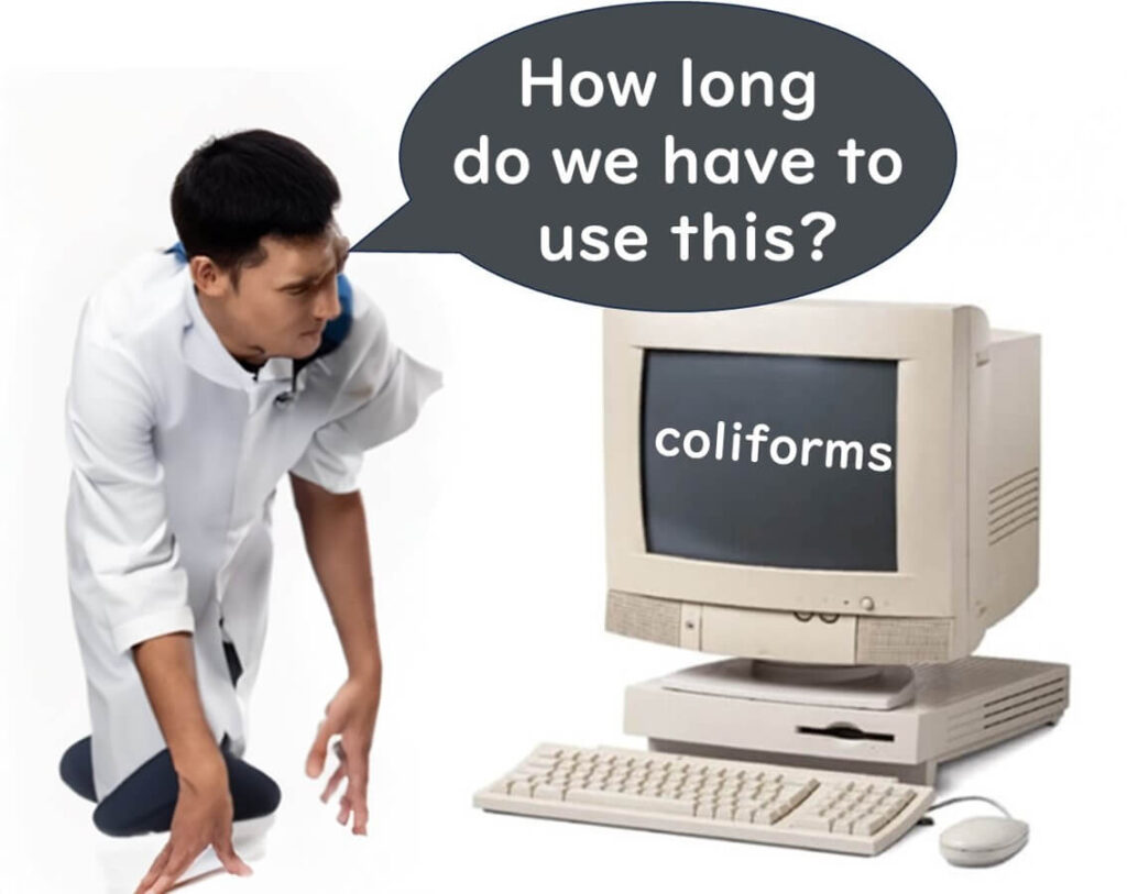 Illustration comparing coliform bacteria to outdated technology, symbolized by an old computer, with a person questioning its continued use.