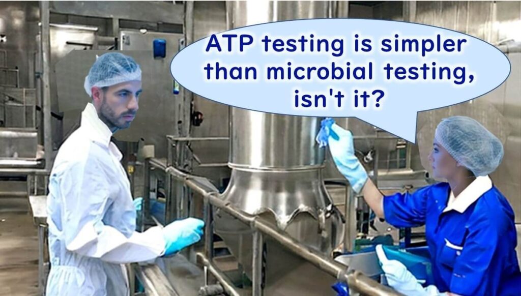 Two employees in a food factory discussing the simplicity of ATP testing compared to microbial testing, with one holding a swab for sample collection.