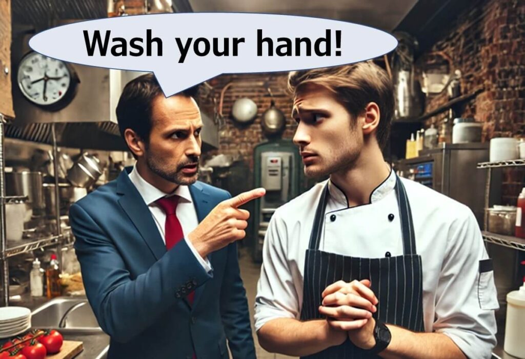 A restaurant manager sternly points at a chef in a professional kitchen, with a speech bubble saying “Wash your hand!” to stress the importance of hygiene.
